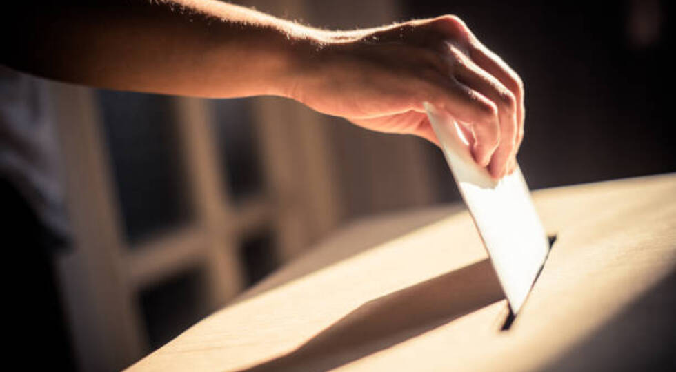 Conceptual image of a person voting, casting a ballot at a polling station, during elections.